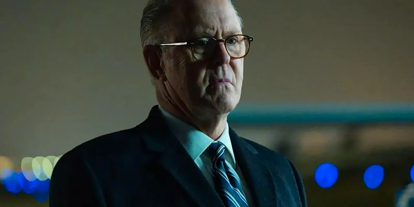 Harold Harper with glasses on in his office, wearing a suit in a scene from The Old Man. Image