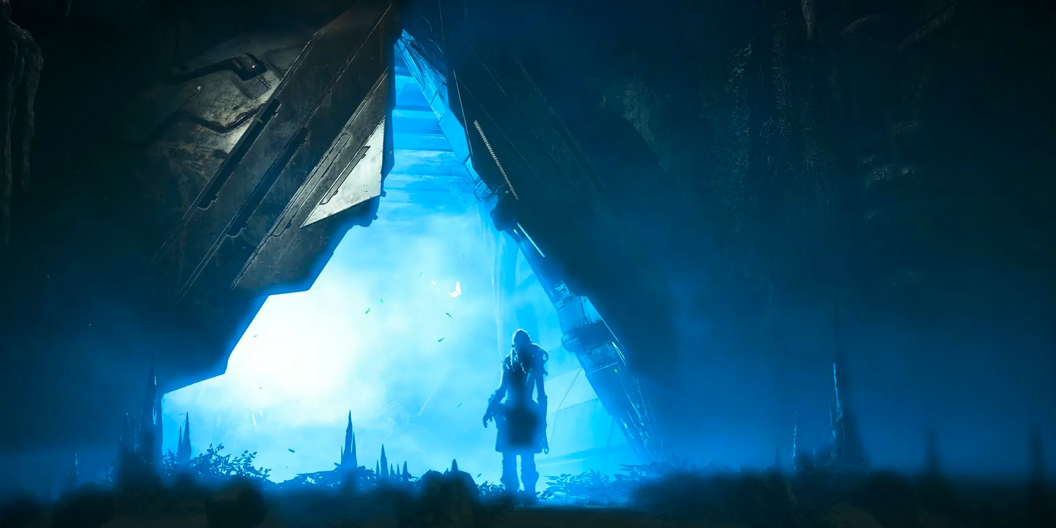 Horizon Zero Dawn Aloy standing in front of a triangle of blue light inside of a high-tech environment. Image