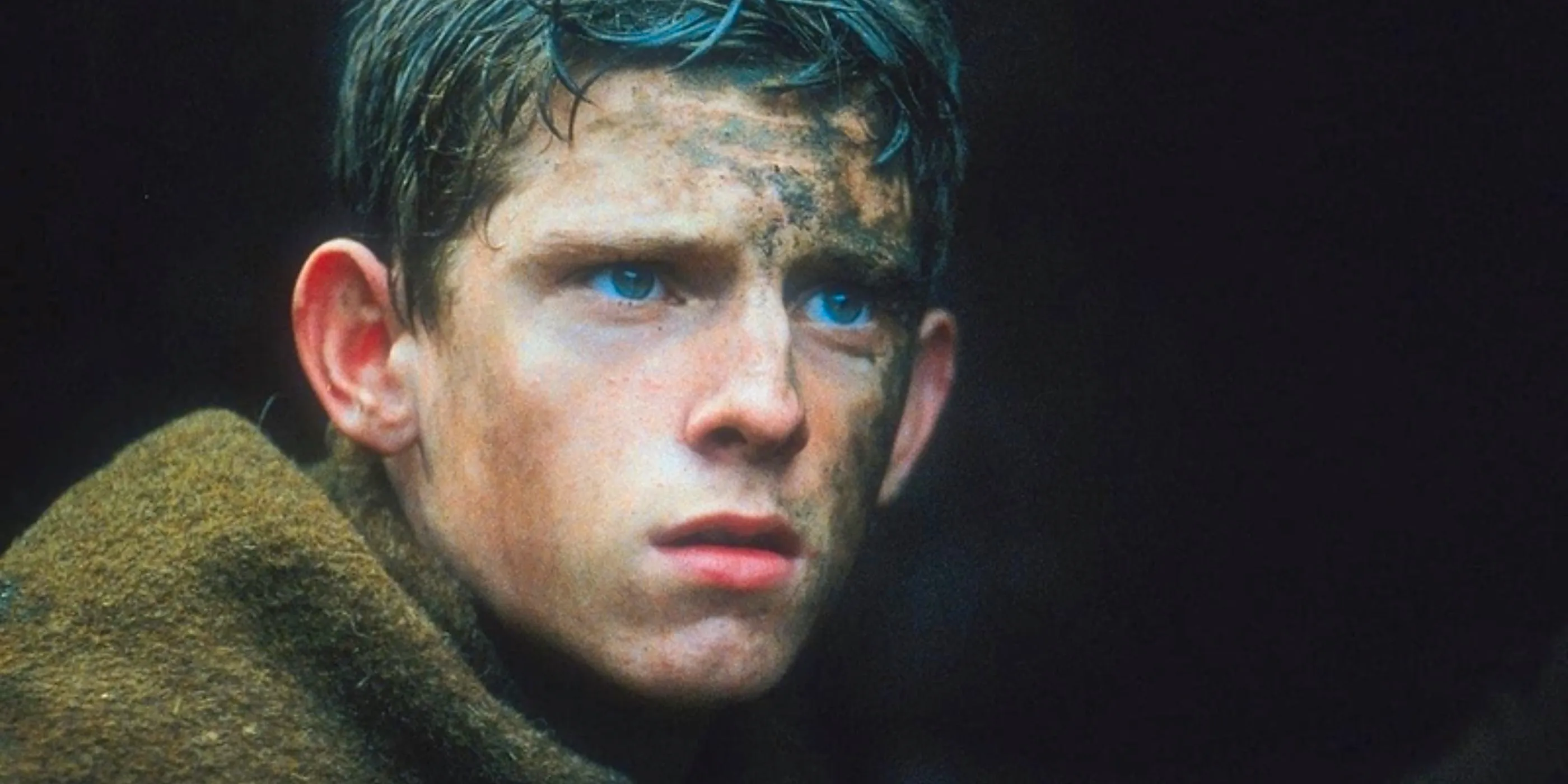 Jamie Bell in khakiand covered in mud looking frightened in Deathwatch Image