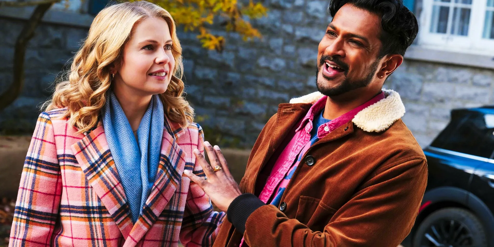 Jay laughs at Samantha in Ghosts as the couple stands outside in fall coats Image