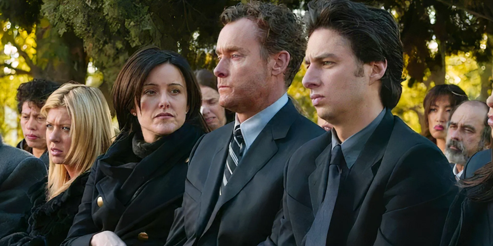 JD, Dr. Cox, Jordan, and Danni all looking sad at Ben's funeral in Scrubs Image