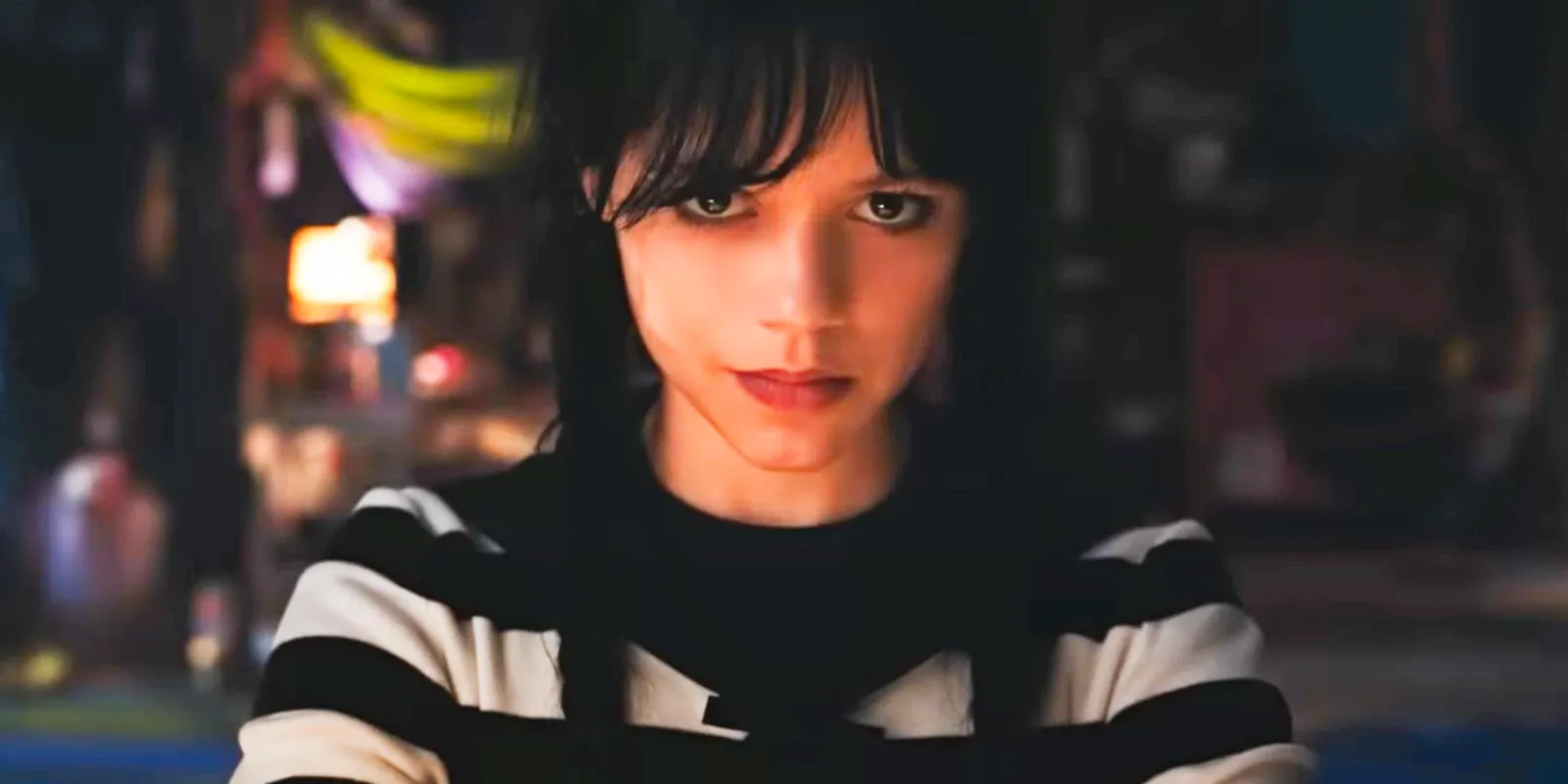 Jenna Ortega as Wednesday Addams wearing a striped shirt and smirking Image