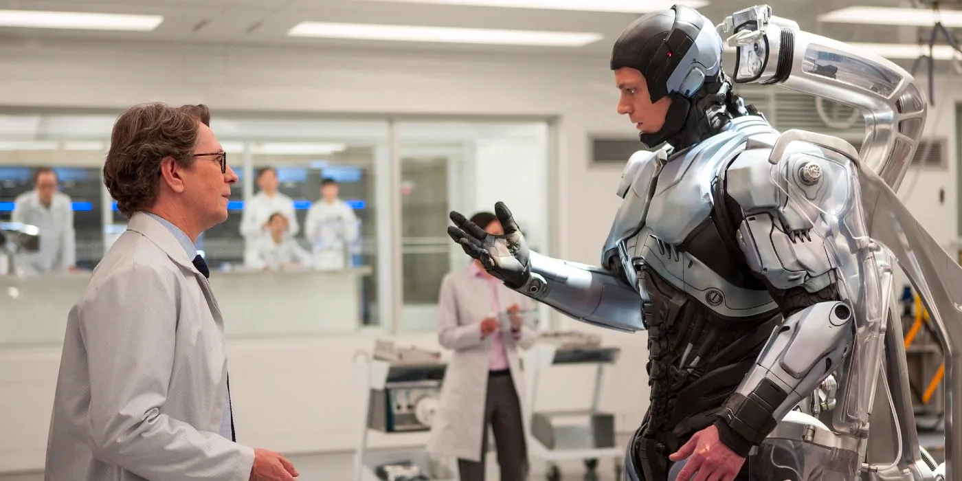 Joel Kinnamon looking at his robotic hand in front of Gary Oldman in 2014's RoboCop. Image