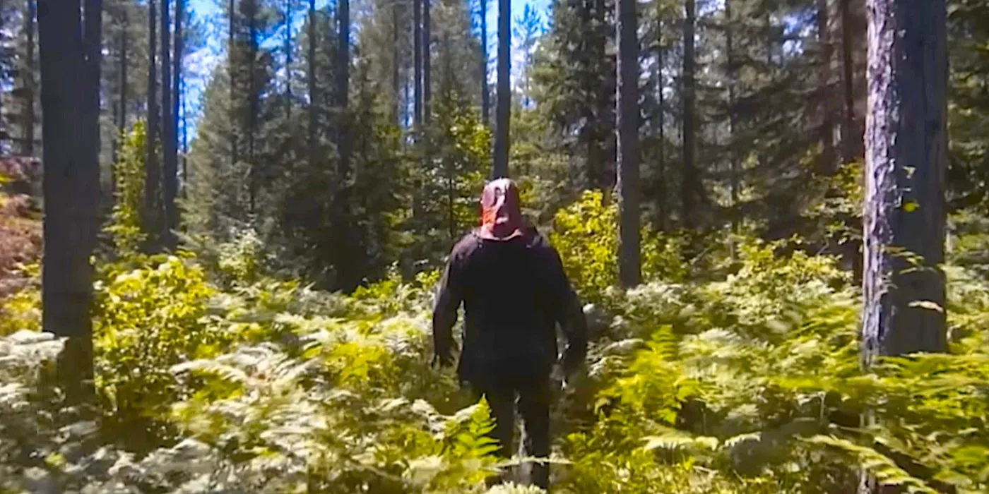 Johnny stands in the woods with his back to the camera in In A Violent Nature Image