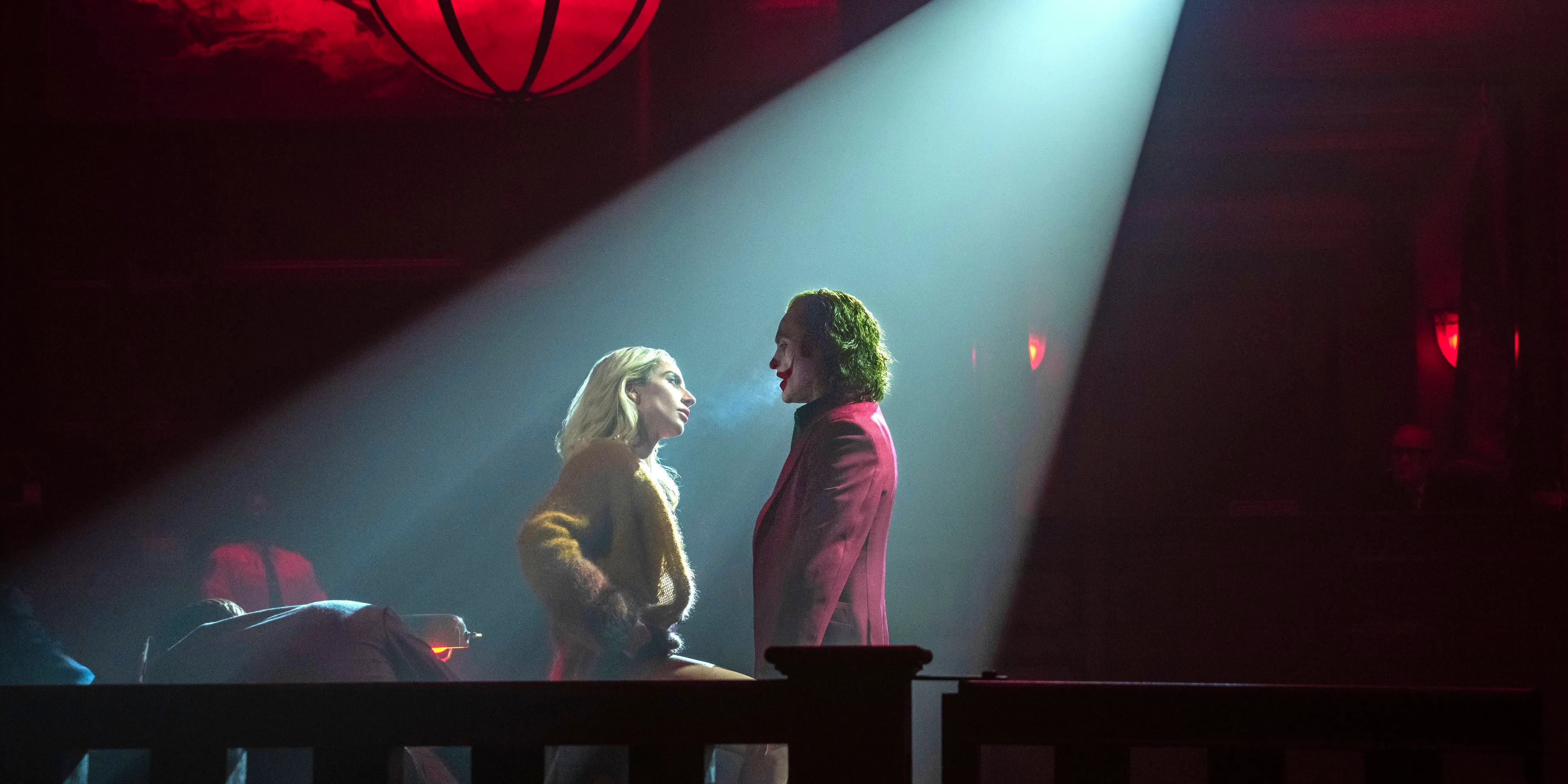 Joker and Harley Quinn face each other in a spotlight in Joker Folie a Deux Image