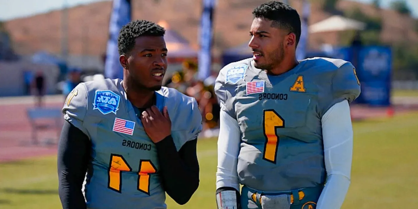 Jordan (Michael Evans Behling) and Spencer (Daniel Ezra) standing together on the football field in All American. Image