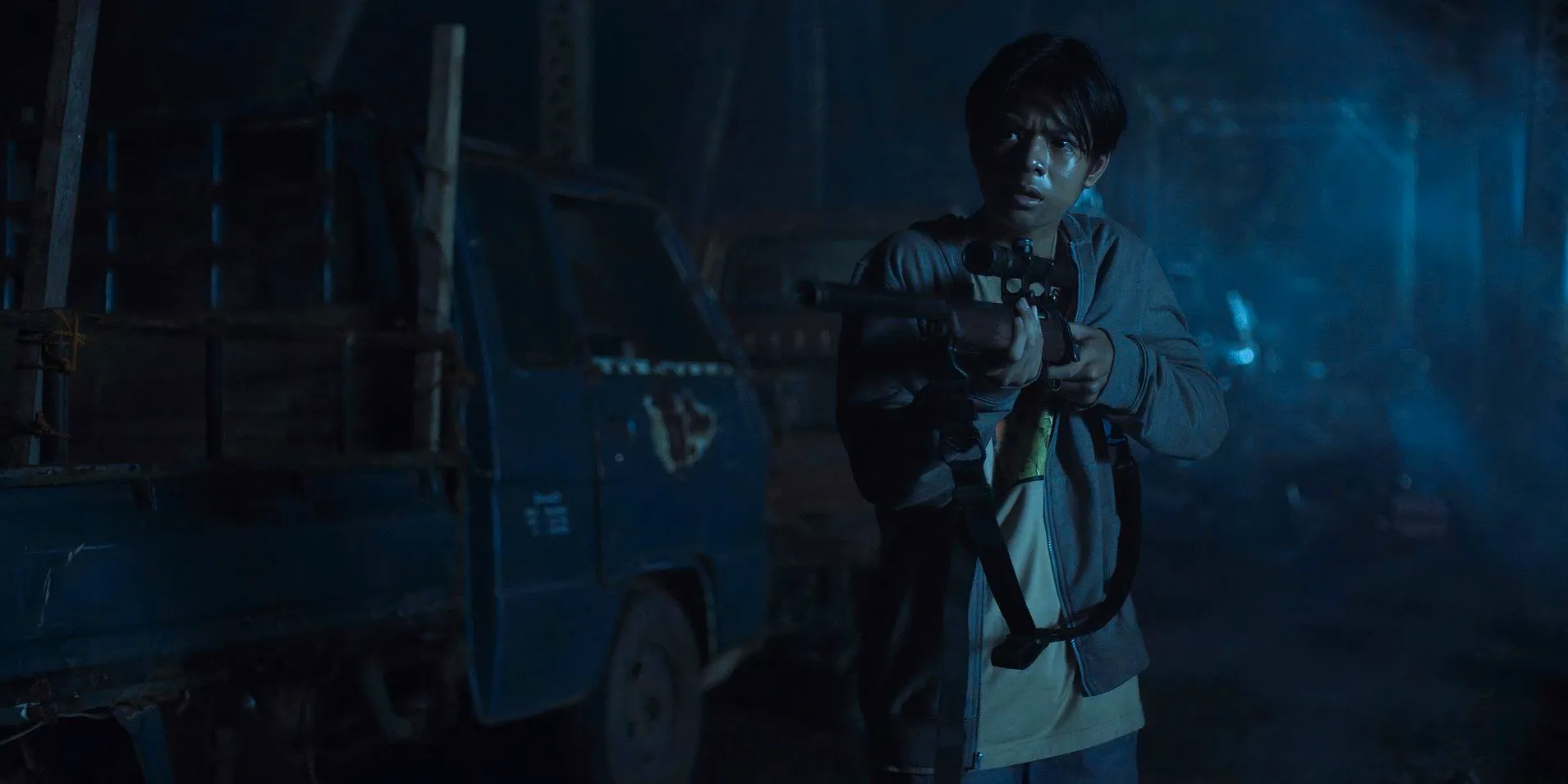 Joshua (Marco Masa) holding a rifle on the bridge in Outside Image