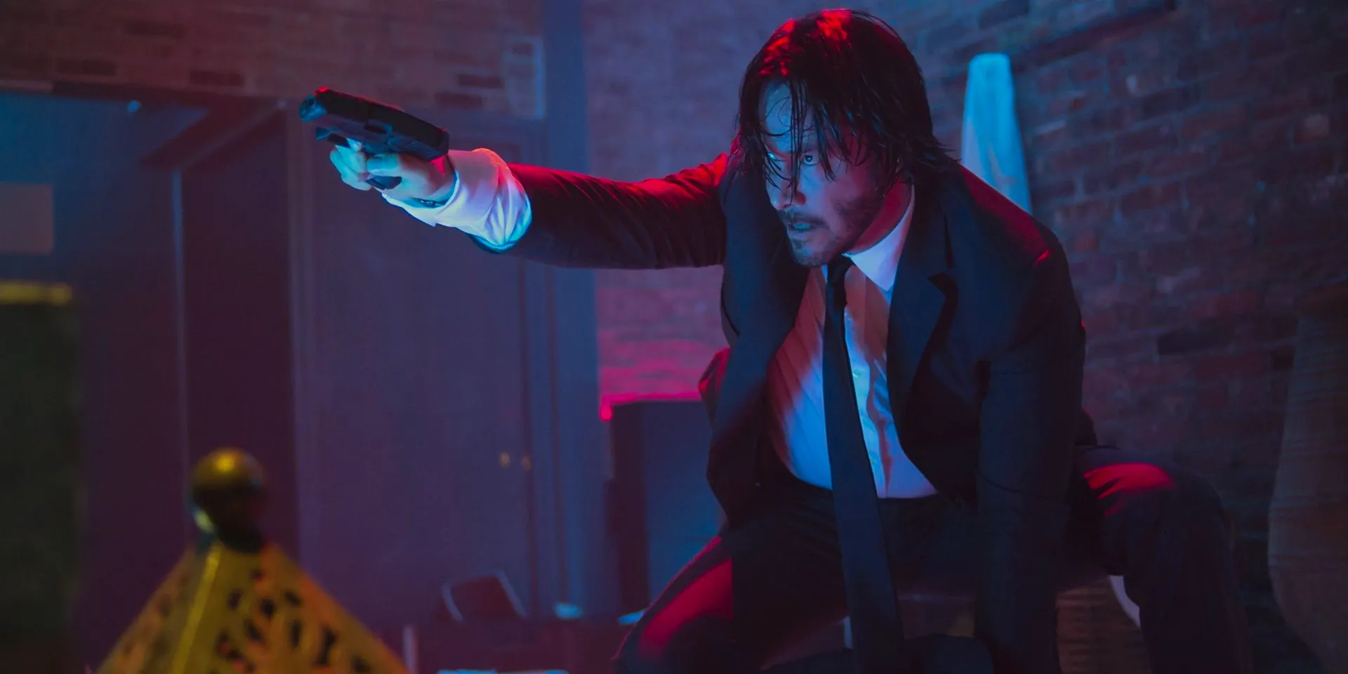 Keanu Reeves with a gun in a club in John Wick Image