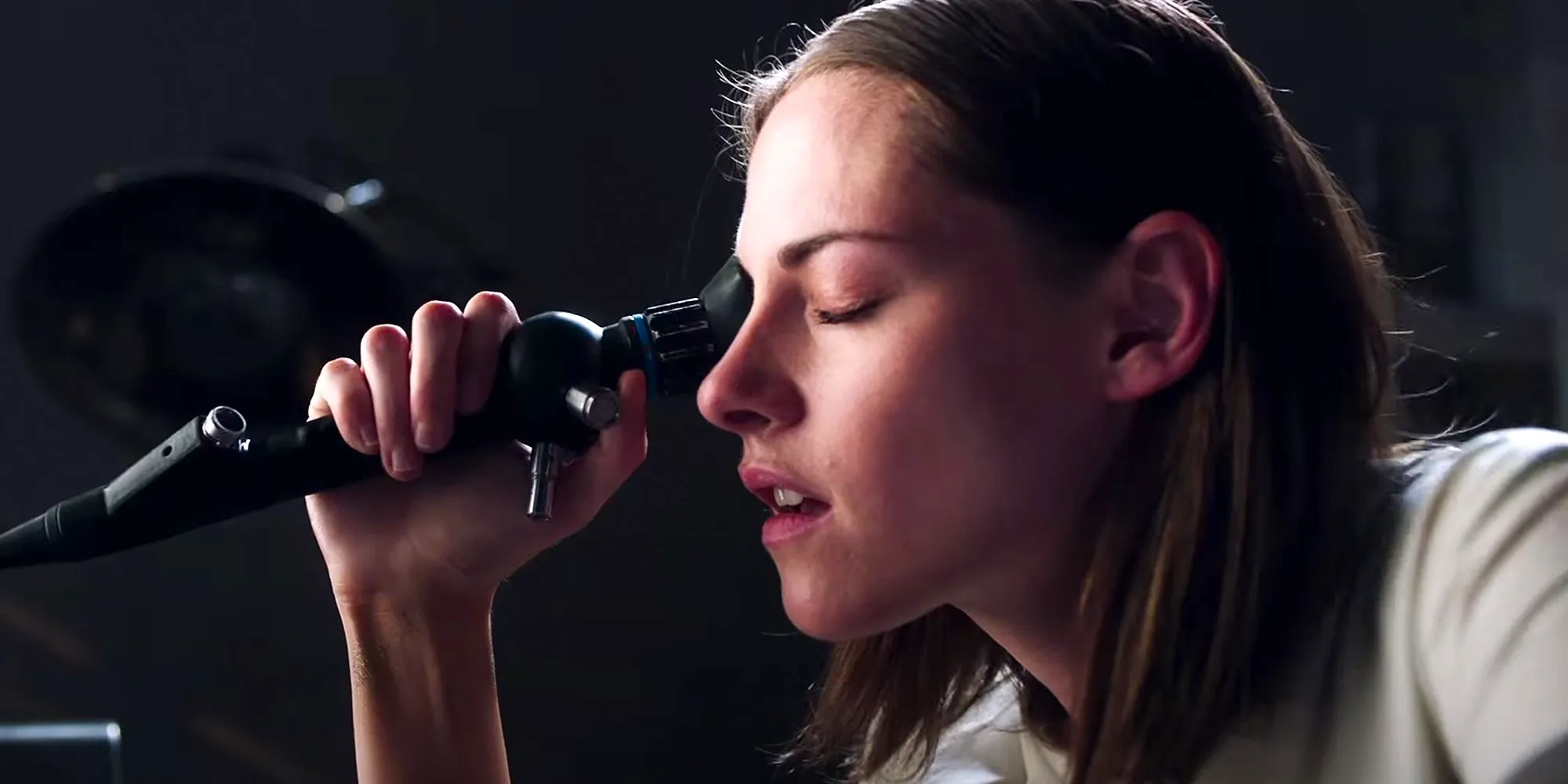 Kristen Stewart in Crimes of the Future looking intently into a microscope  Image