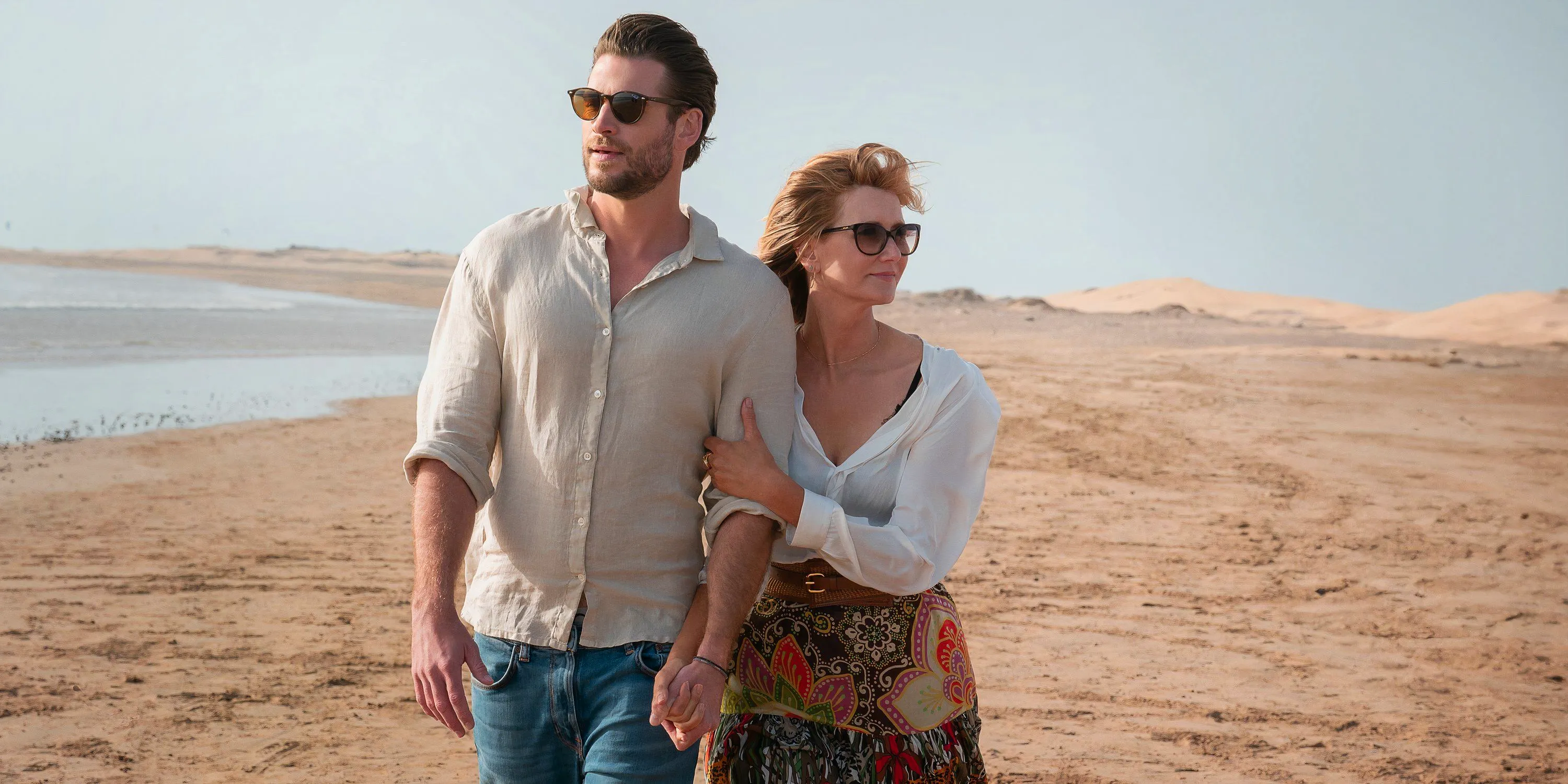 Laura Dern and Liam Hemsworth walk on the beach in Lonely Planet Image