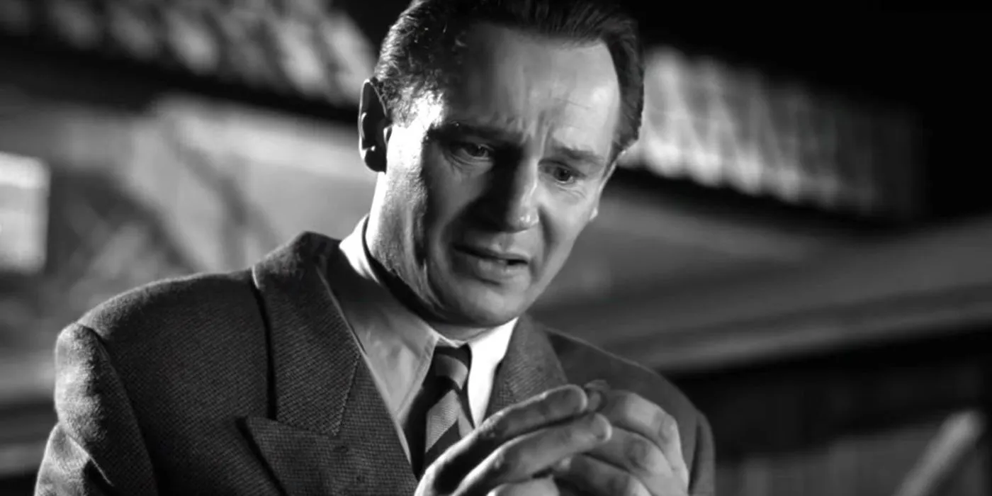 Liam Neeson as Oskar looking sad at a watch in Schindlers List. Image