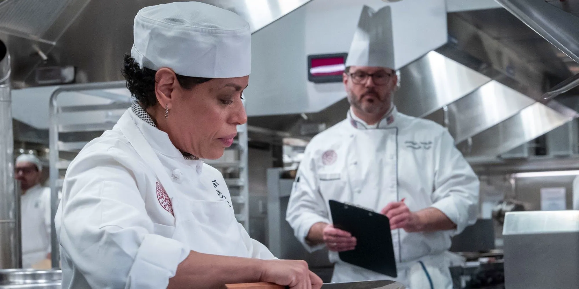 Liza Colon-Zayas as Tina cooks as a teacher watches in The Bear season 2 episode 5 Image