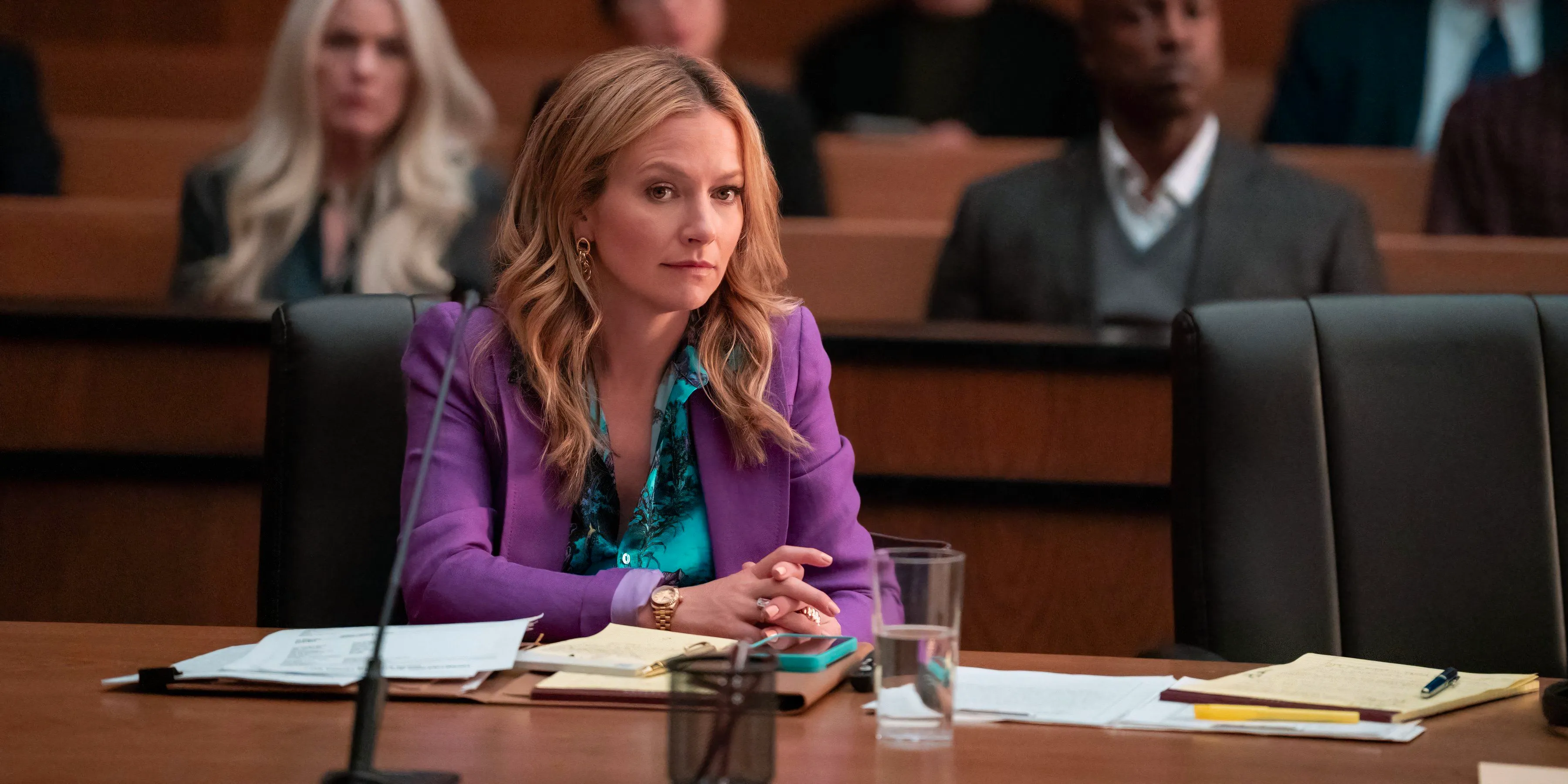 Lorna is in the courtroom wearing a purple suit with a bright blue button-up shirt underneath in The Lincoln Lawyer Image