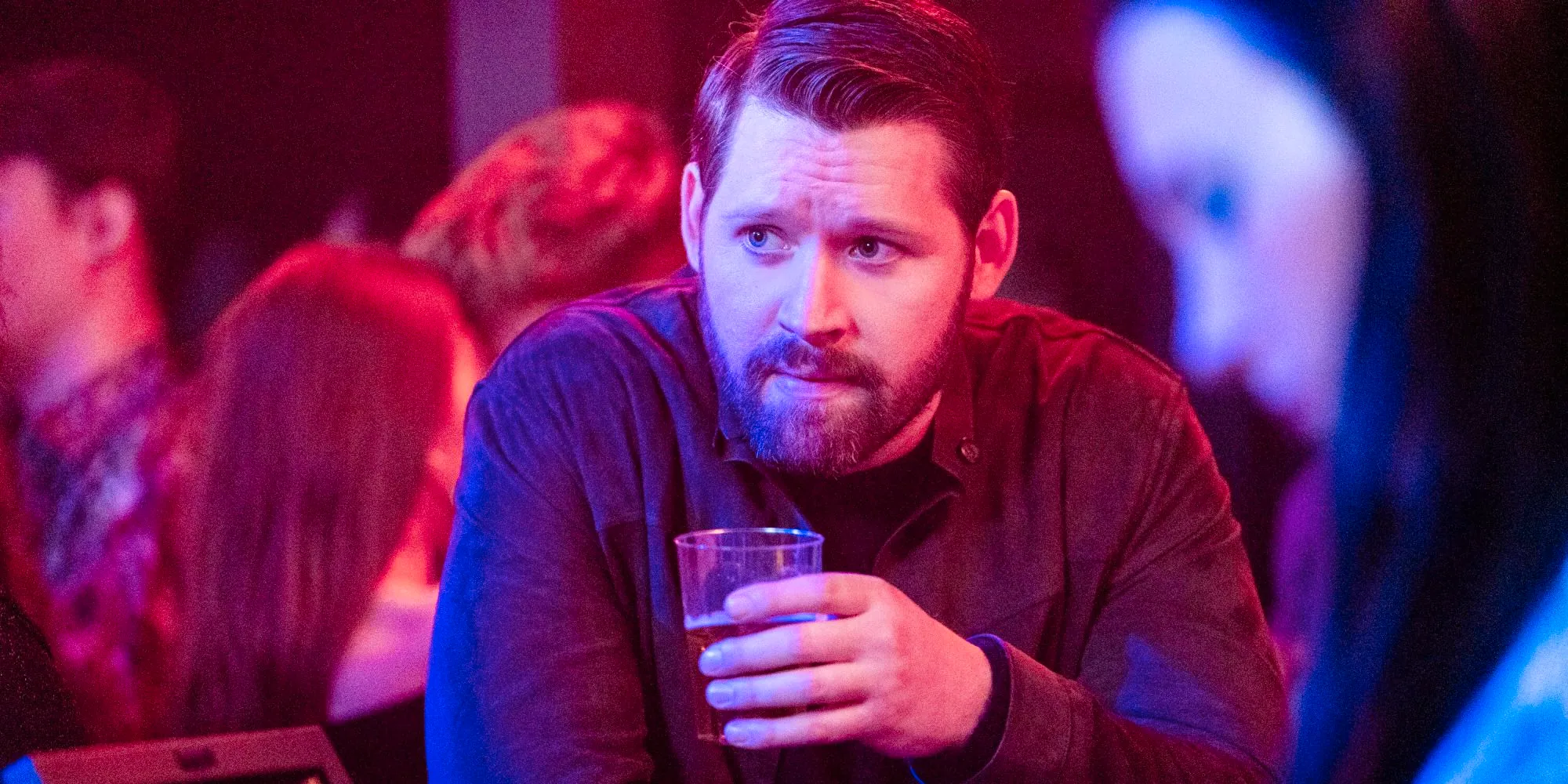 Luke Kleintank as Scott Forrester sips a drink on FBI: International season 3 Image