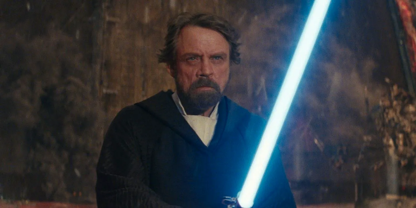 Luke Skywalker in Star Wars The Last Jedi holding Anakin's blue lightsaber Image