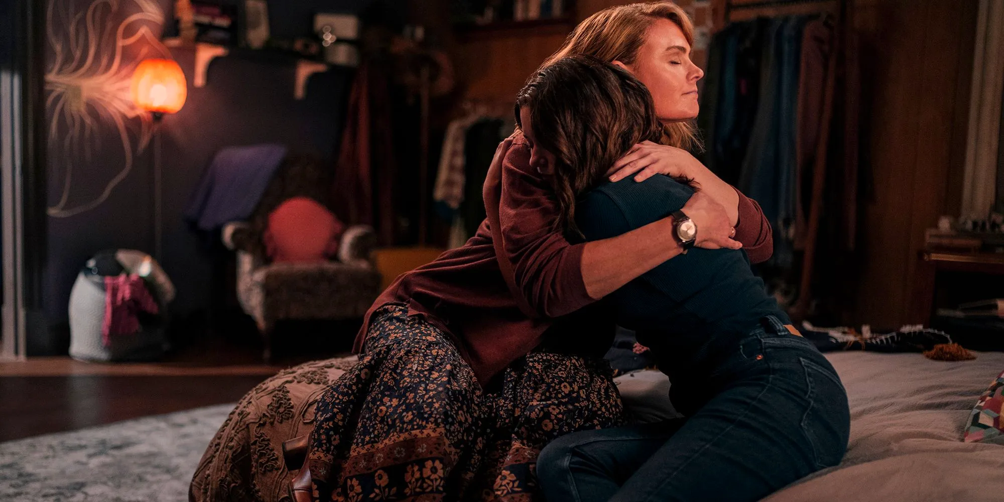 Mae (Madeleine Arthur) and Suzanne (Emily Deschanel) hug on the bed in Devil in Ohio Image