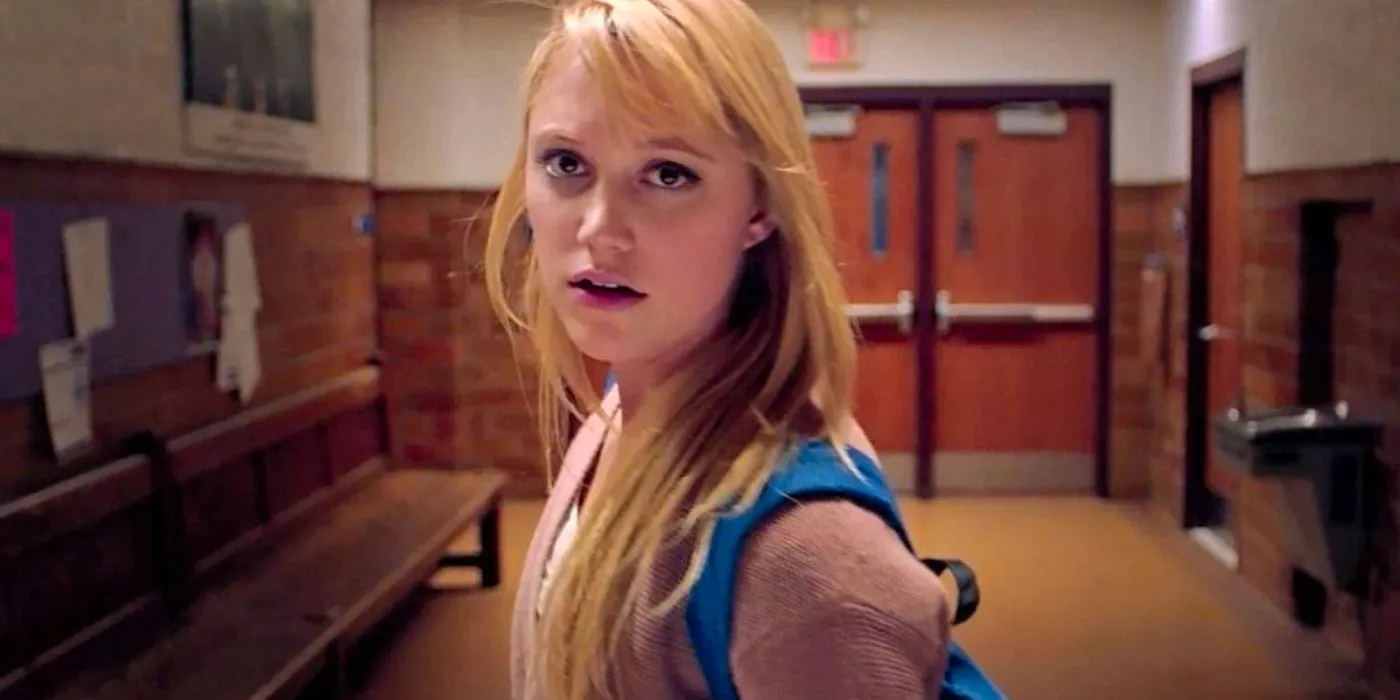 Maika Monroe as Jay Height standing in a school hallway in It Follows Image