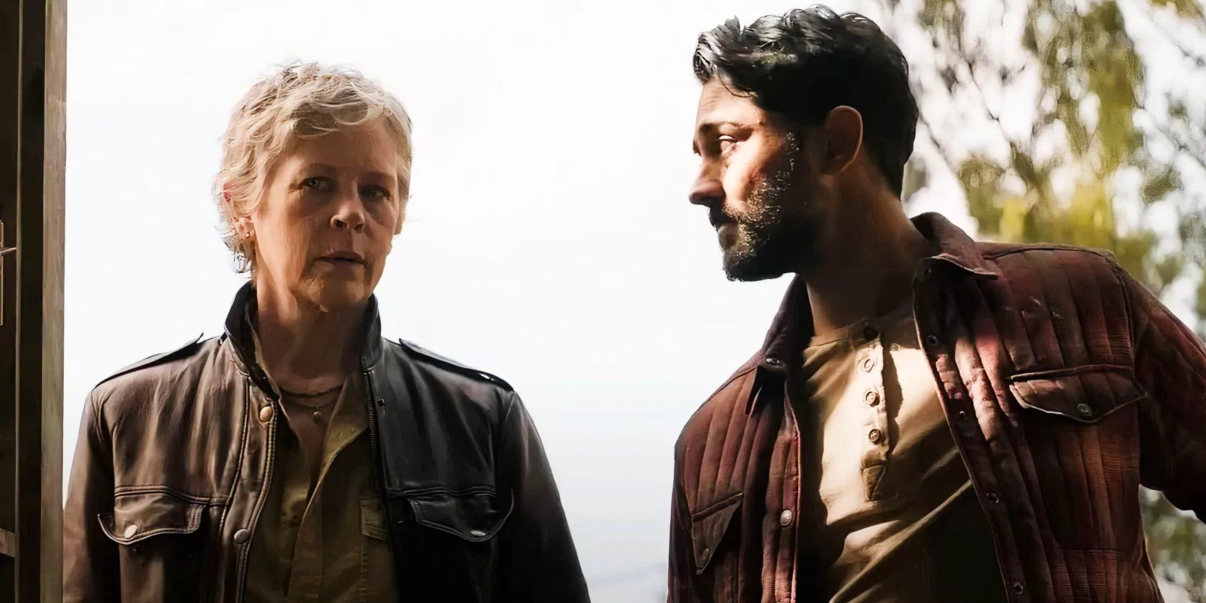 Manish Dayal as Ash looking at Melissa McBride as Carol in The Walking Dead Daryl Dixon season 2 Image