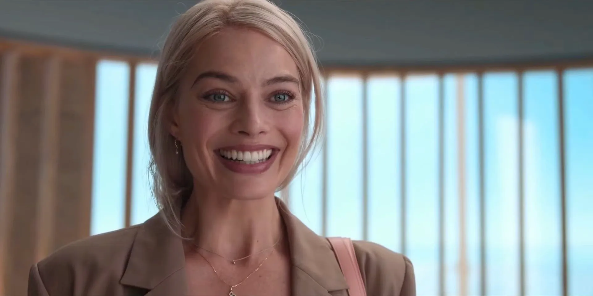 Margot Robbie smiling in the final scene of Barbie (2023). Image