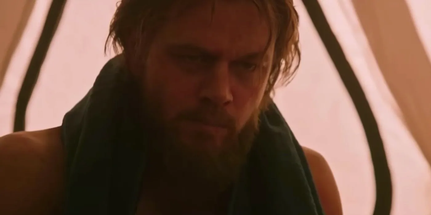 Mark Watney (Matt Damon) with long hair and a beard eating in The Martian. Image