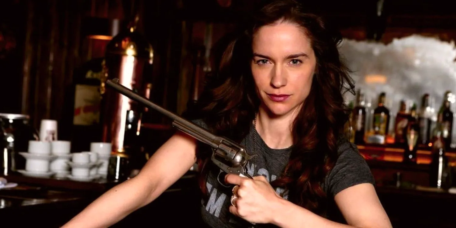 Melanie Scrofano sits in a bar with Peacemaker in Wynonna Earp Image