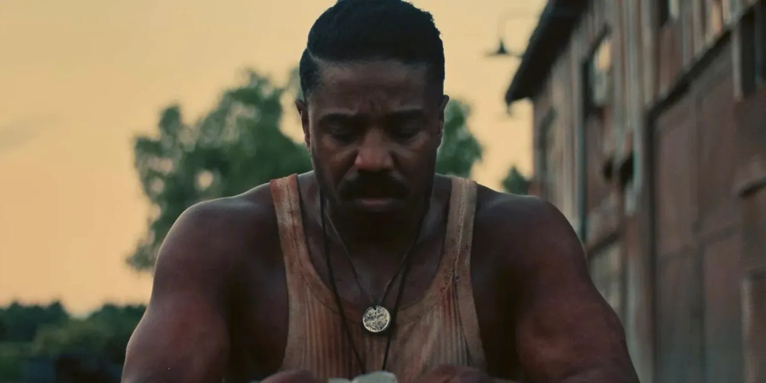 Michael B. Jordan bloodied and looking upset in Sinners Image