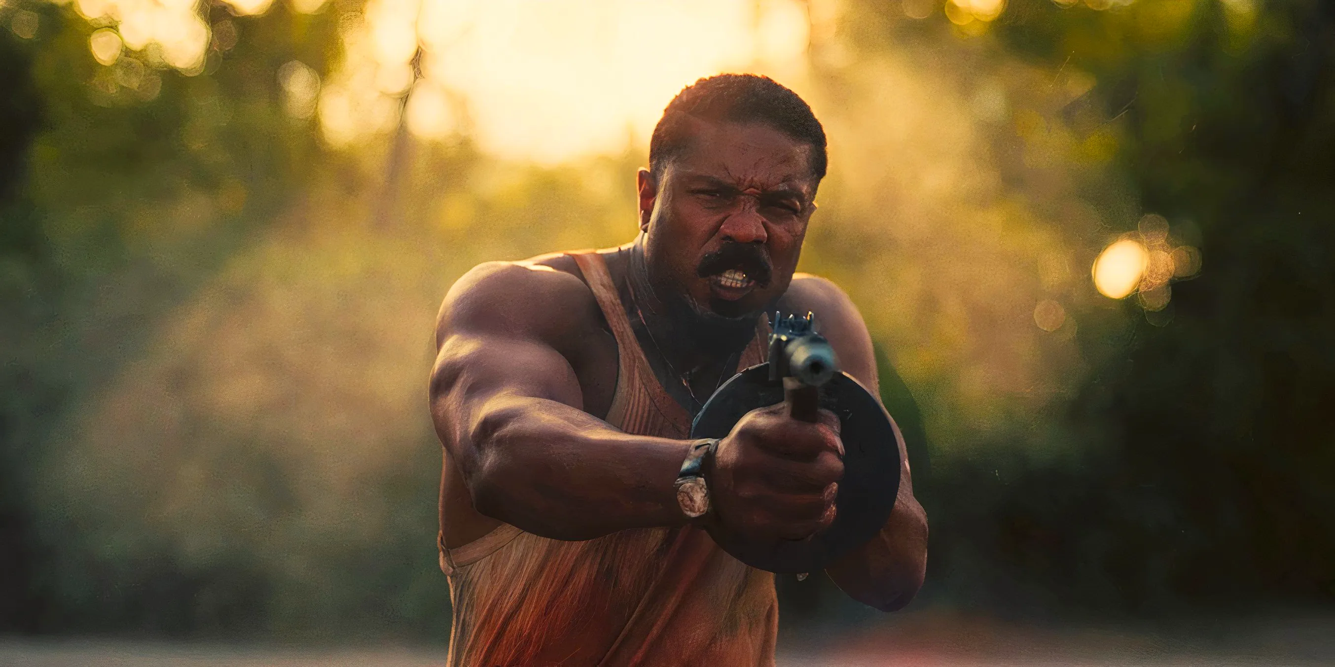 Michael B Jordan firing a machine gun in Sinners Image