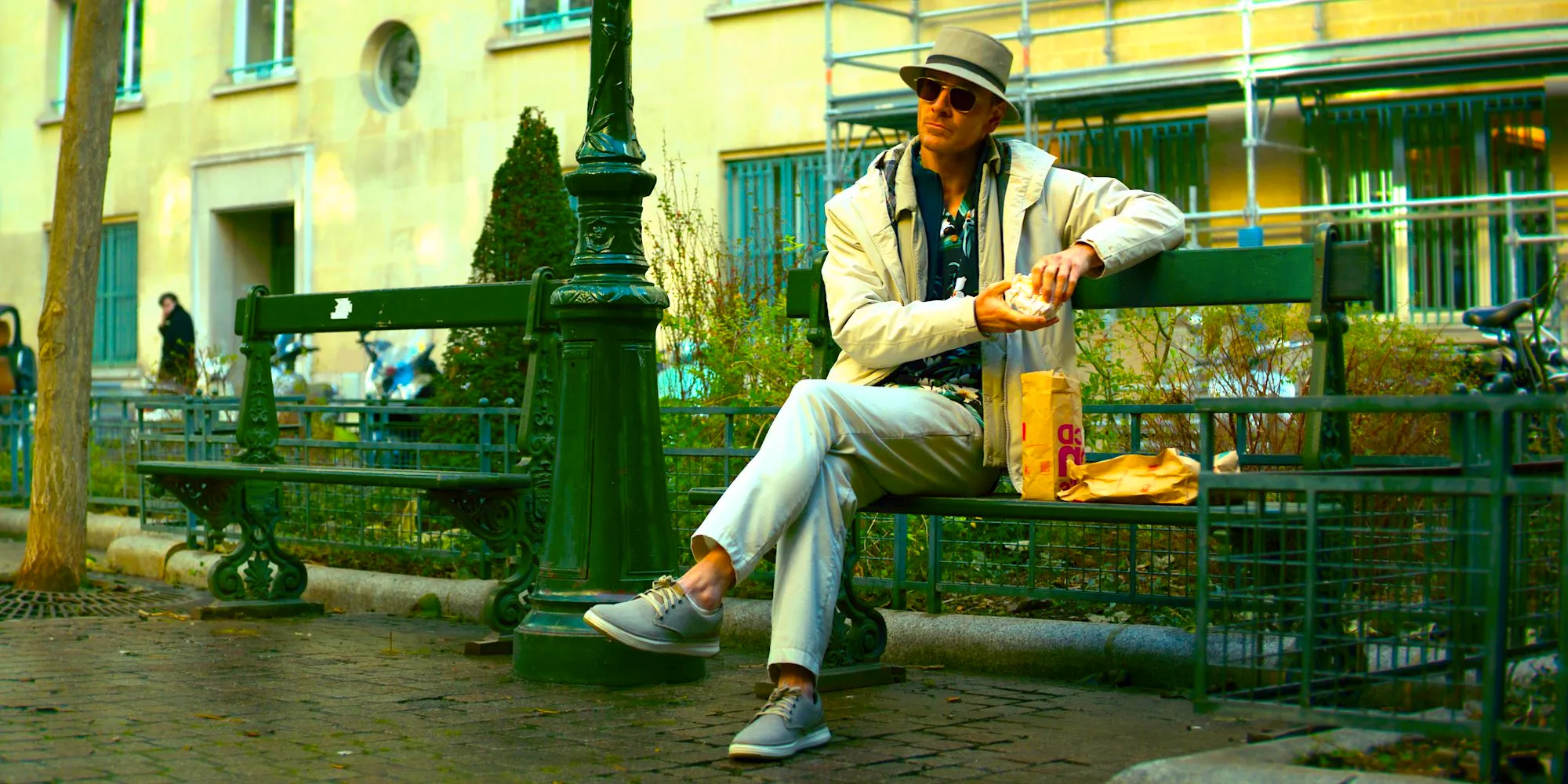 Michael Fassbender sitting on a bench in David Fincher's The Killer  Image