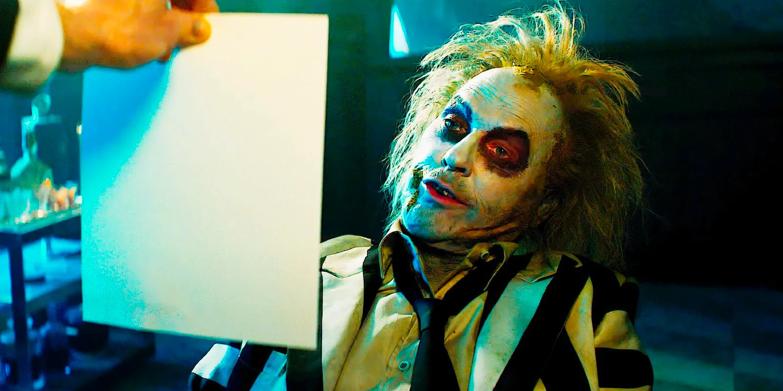 Michael Keaton as Beetlejuice looking at a piece of paper in Beetlejuice Beetlejuice Image