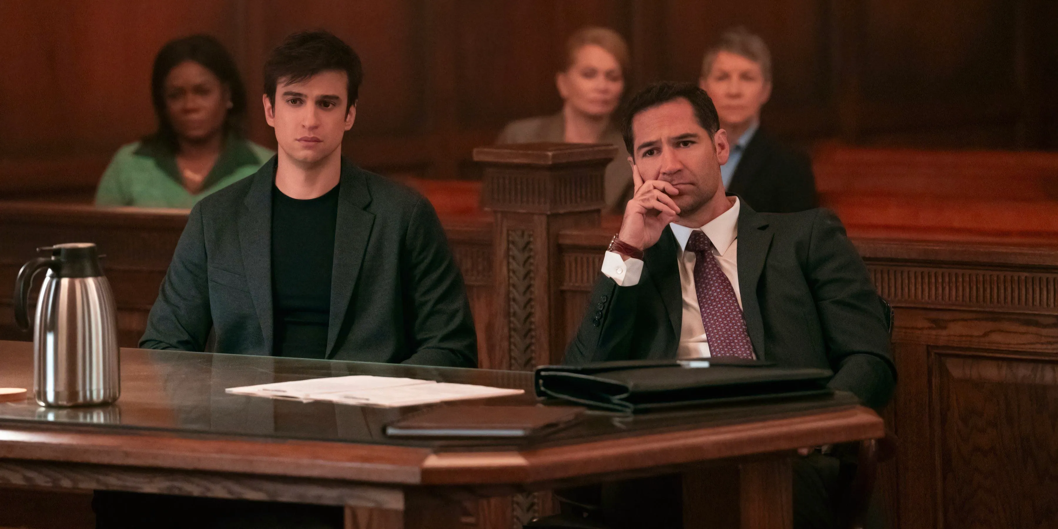 Mickey and Eddie sit at the defense's table in court in The Lincoln Lawyer season 3. Image