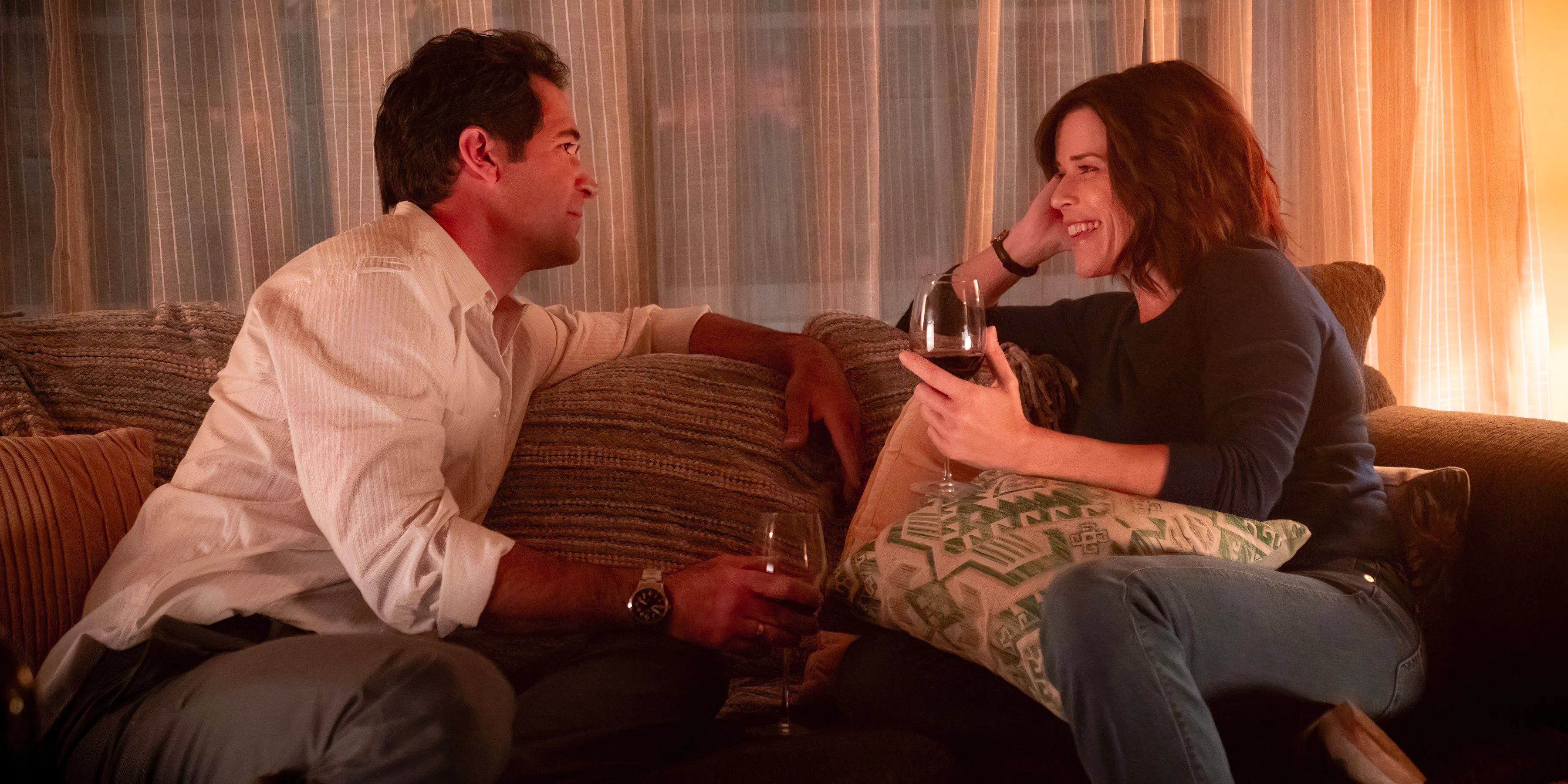 Mickey and Maggie drink wine while sitting on the couch in The Lincoln Lawyer season 3 episode 1 Image