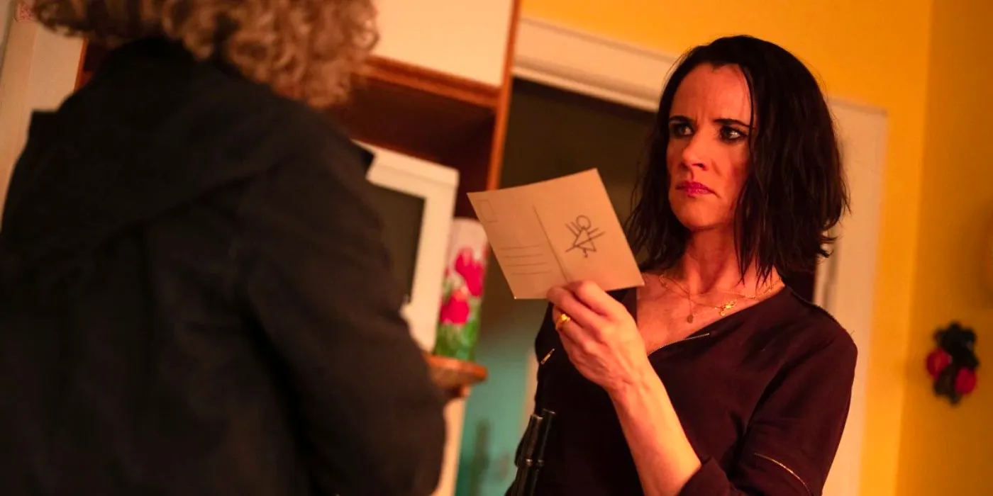 Natalie (Juliette Lewis) holding a postcard with the mysterious symbol on Yellowjackets Image