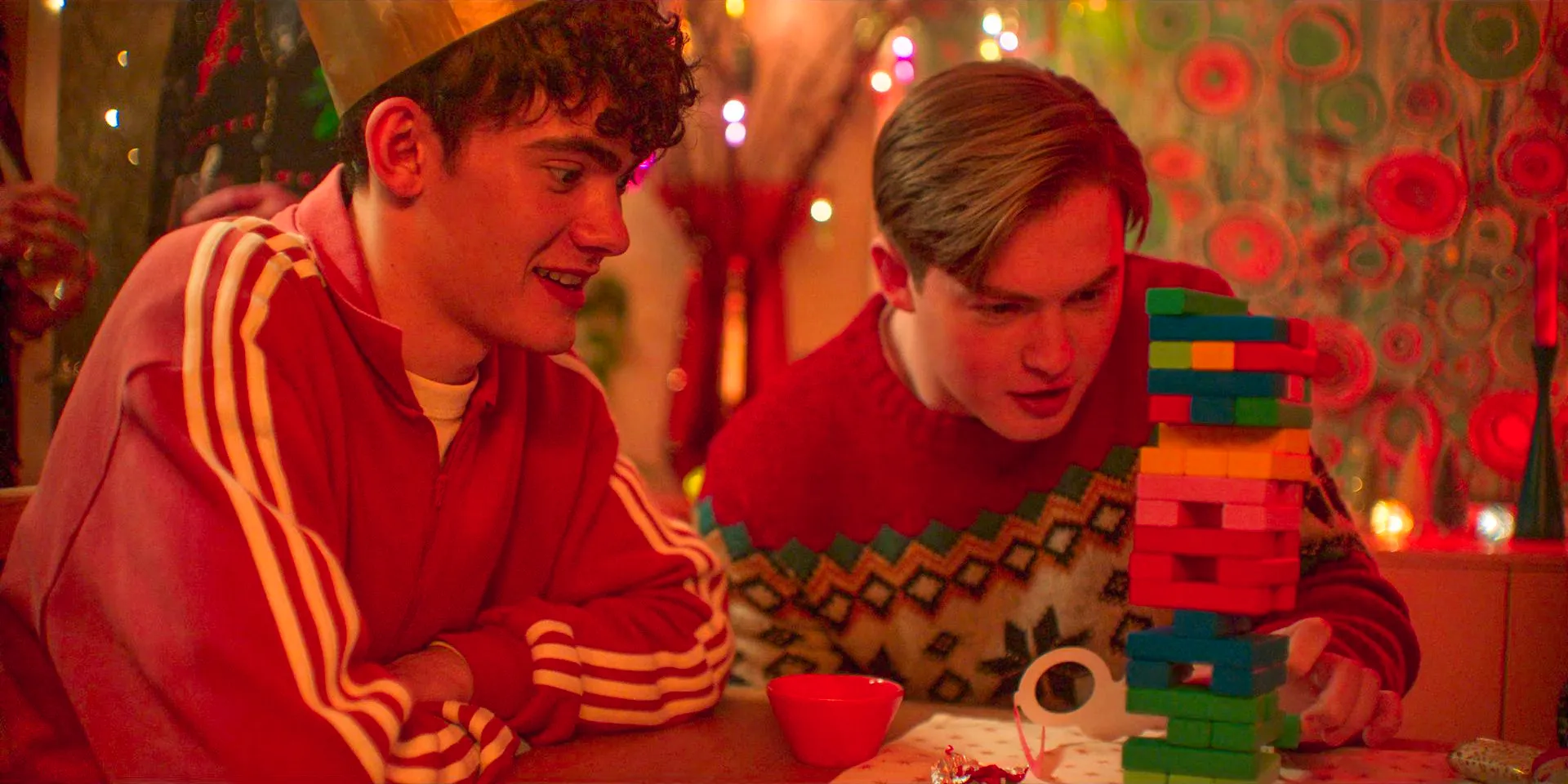 Nick (Kit Connor) and Charlie (Joe Locke) playing Jenga on Christmas in Heartstoppers Season 3 Episode 5 Image