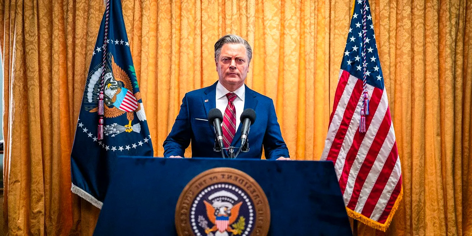  Nick Offerman as the President in Civil War. He is wearing a suit and standing at the presidential podium. Image