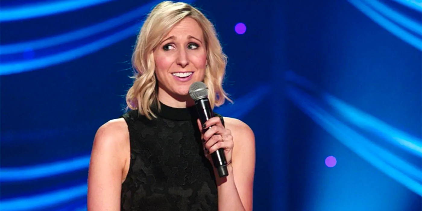 Nikki Glaser performing stand-up with a blue background Image