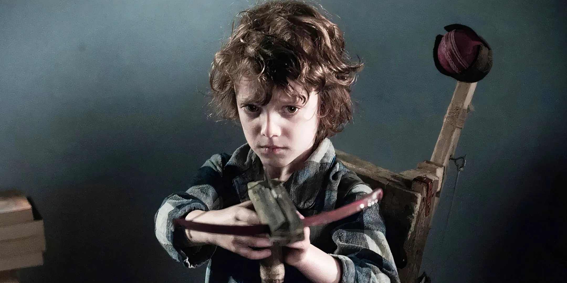 Noah Wiseman as Samuel aiming a crossbow in The Babadook Image