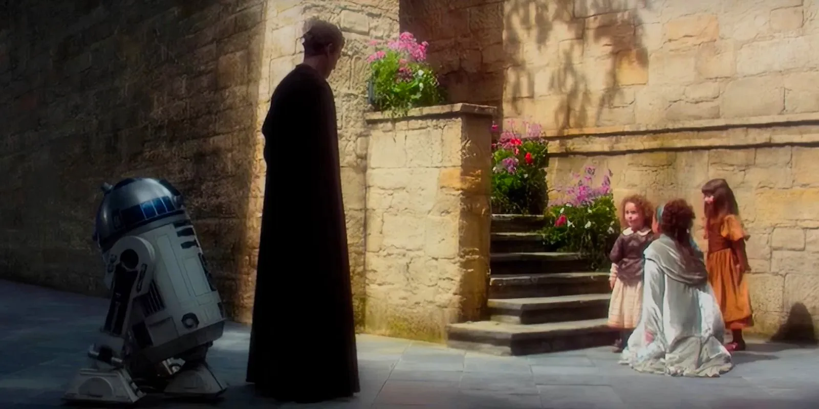 Padme crouching down in front of her nieces, Pooja and Ryoo, with Anakin Skywalker and R2-D2 looking on Image