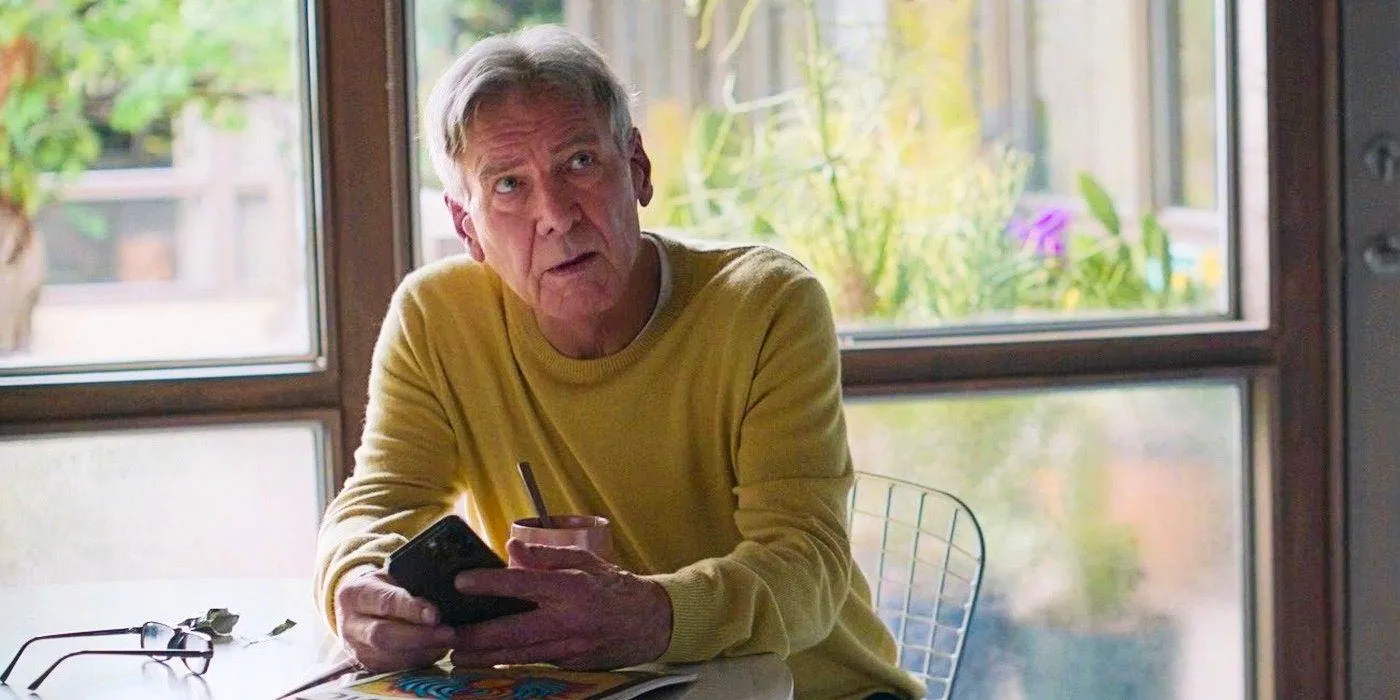 Paul (Harrison Ford) sitting at a table with his cell phone looking annoyed in Shrinking Image