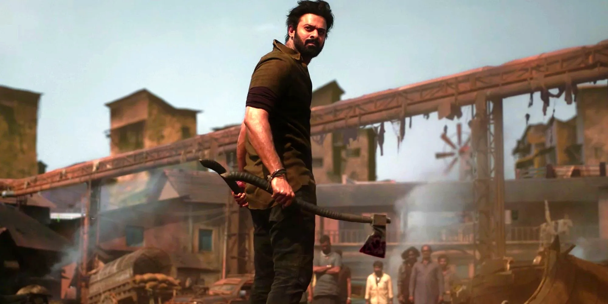 Prabhas as Salaar standing among ruins holding an axe and looking over his shoulder in Salaar Part 1 - Ceasefire. Image