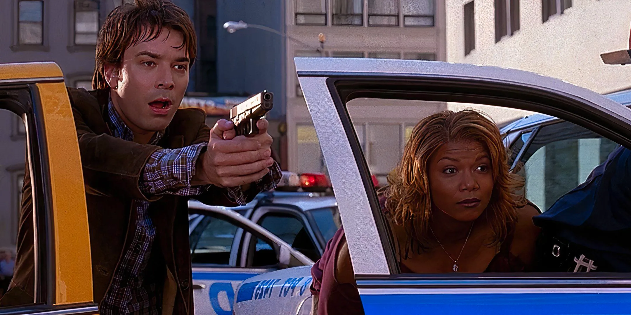 Queen Latifah's Belle and Jimmy Fallon's Washburn looking surprised while taking cover behind car doors in Taxi Image