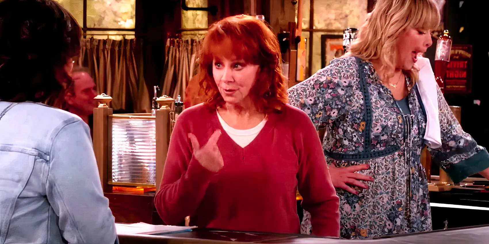 Reba points the finger at herself while at the bar in Happy's Place Image