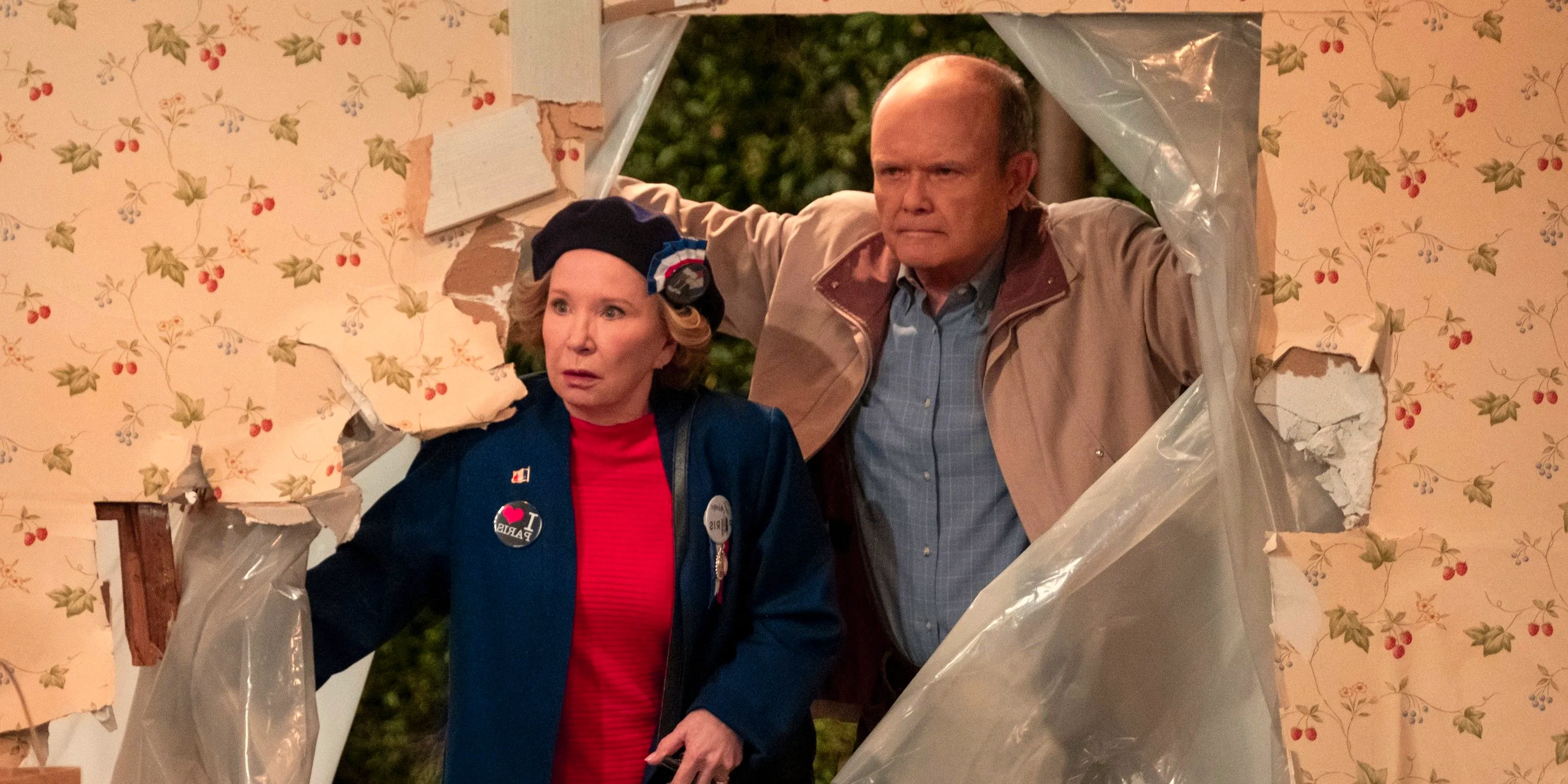 Red (Kurtwood Smith) and Kitty Forman (Debra Jo Rupp) walking through a hole in their kitchen wall in That '90s Show part 3 Image