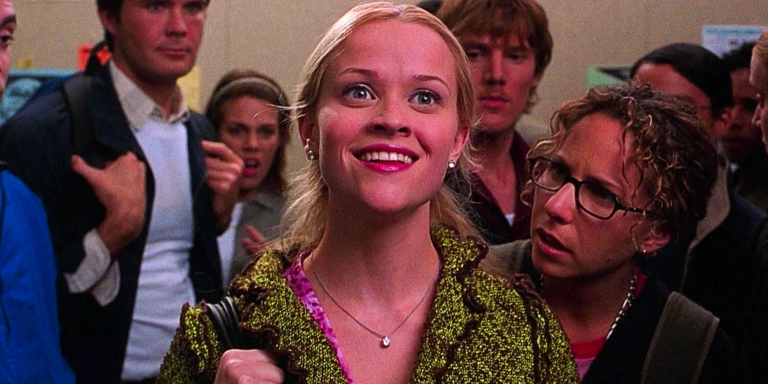 Reese Witherspoon as Elle Woods smiling brightly up at the internship list with a crowd of students around her in Legally Blonde Image