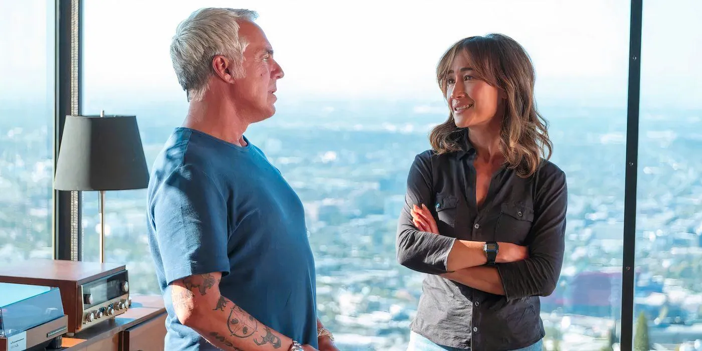 Renee Ballard (Maggie Q) and Harry Bosch (Titus Welliver) talk near a window on Bosch: Legacy season 3 Image