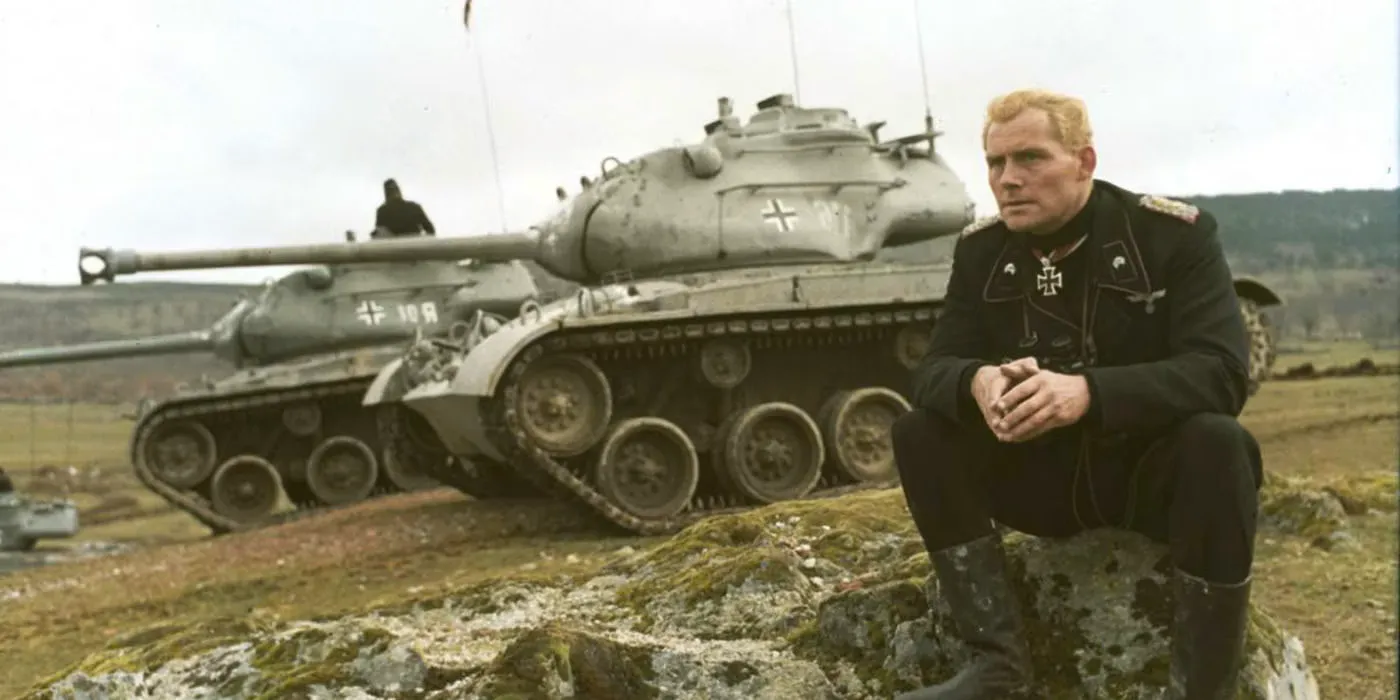 Robert Shaw as Col. Martin Hessler sits on rock in foreground with the Jumbo tank in the background in Battle of the Bulge. Image