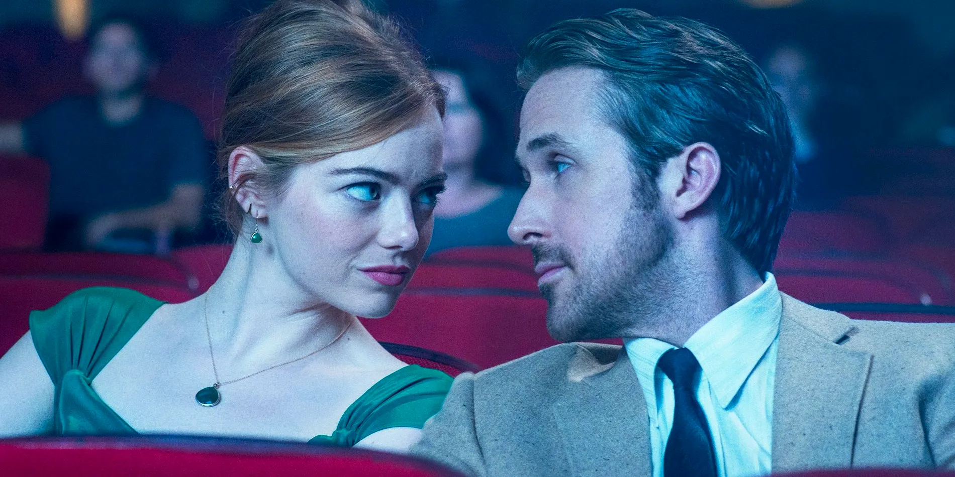 Ryan Gosling as Seb and Emma Stone as Mia looking at each other in a movie theater in La La Land Image