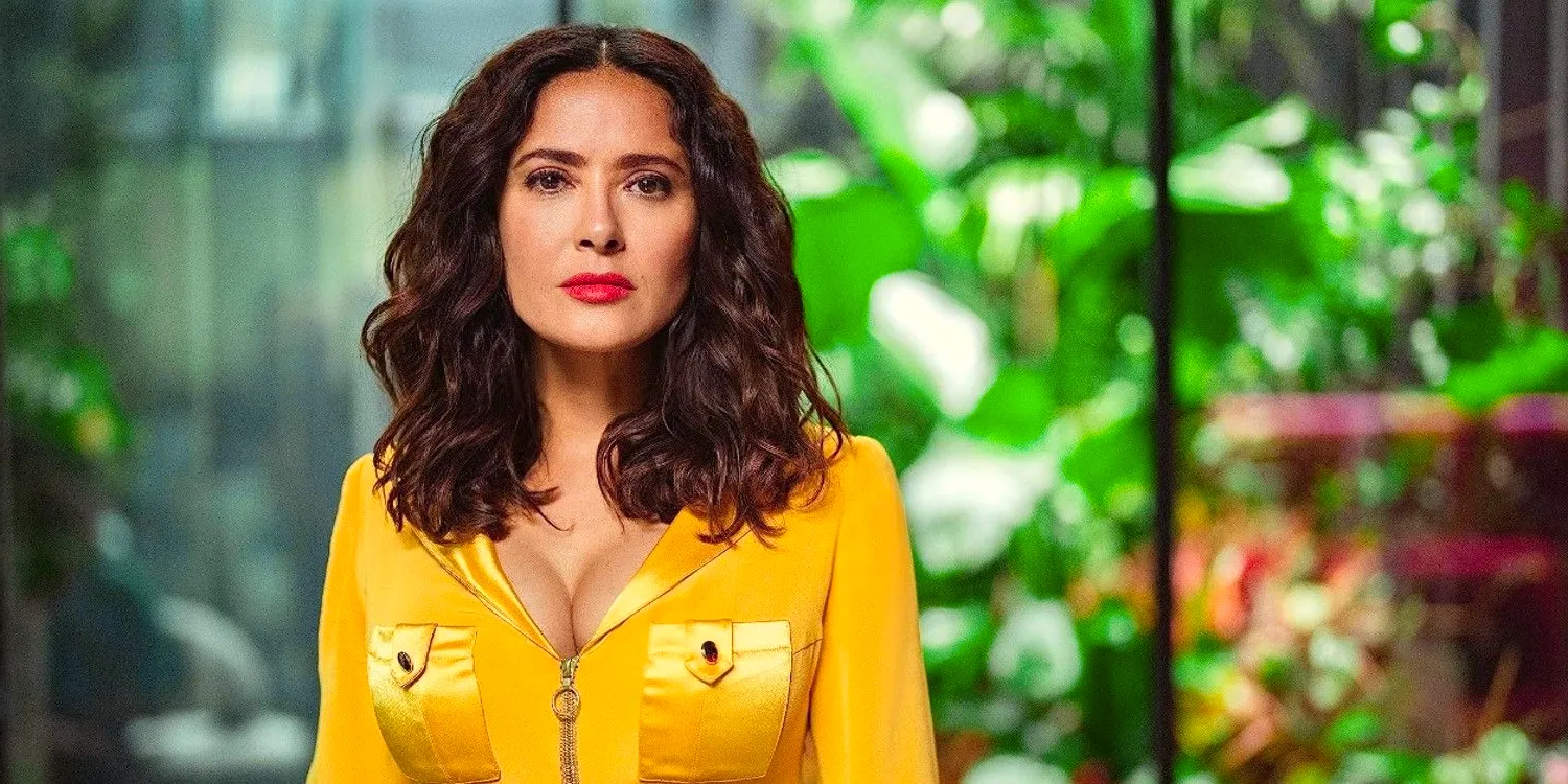 Salma Hayek looks seriously toward the camera while wearing a yellow jumpsuit in Black Mirror Image