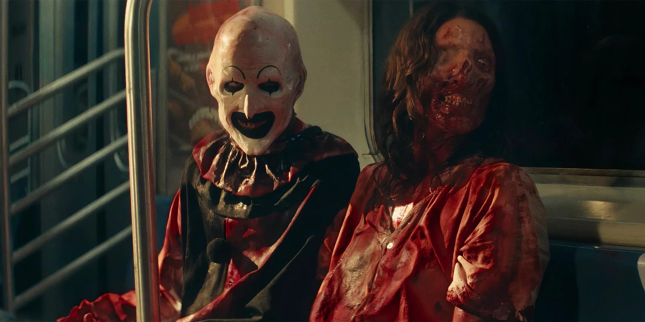 Samantha Scaffidi's Vicky and David Howard Thornton's Art the Clown smiling and covered in blood while sitting on a bus in Terrifier 3 Image