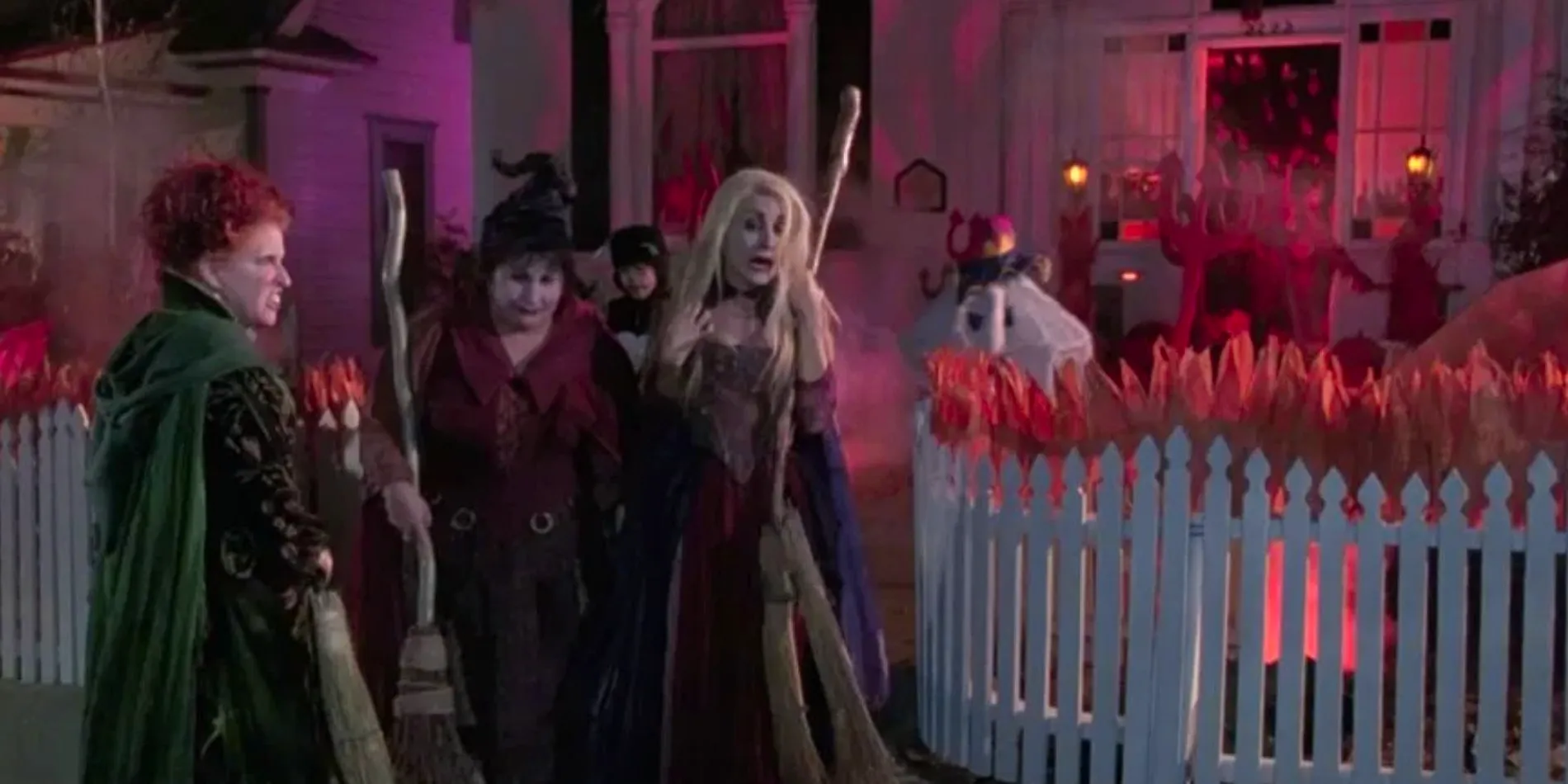 Sarah, Mary, and Winifred Sanderson outside a house while kids trick-or-treat in Hocus Pocus Image