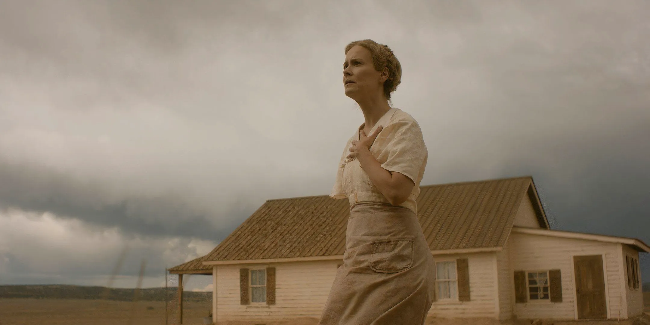 Sarah Paulson as Margaret looking suspiciously with her hand on her chest and the house in the background in Hold Your Breath Image